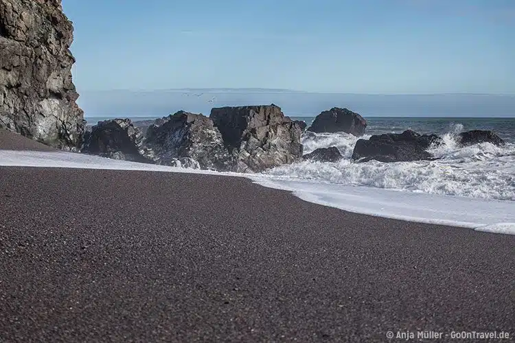 Feinkörniger schwarzer Sand am Strand