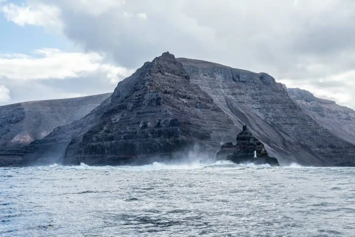 Die beeindruckende Gebirgskette Risco de Famara und Punta Fariones mit Leuchtturm Die beeindruckende Gebirgskette Risco de Famara und Punta Fariones mit Leuchtturm