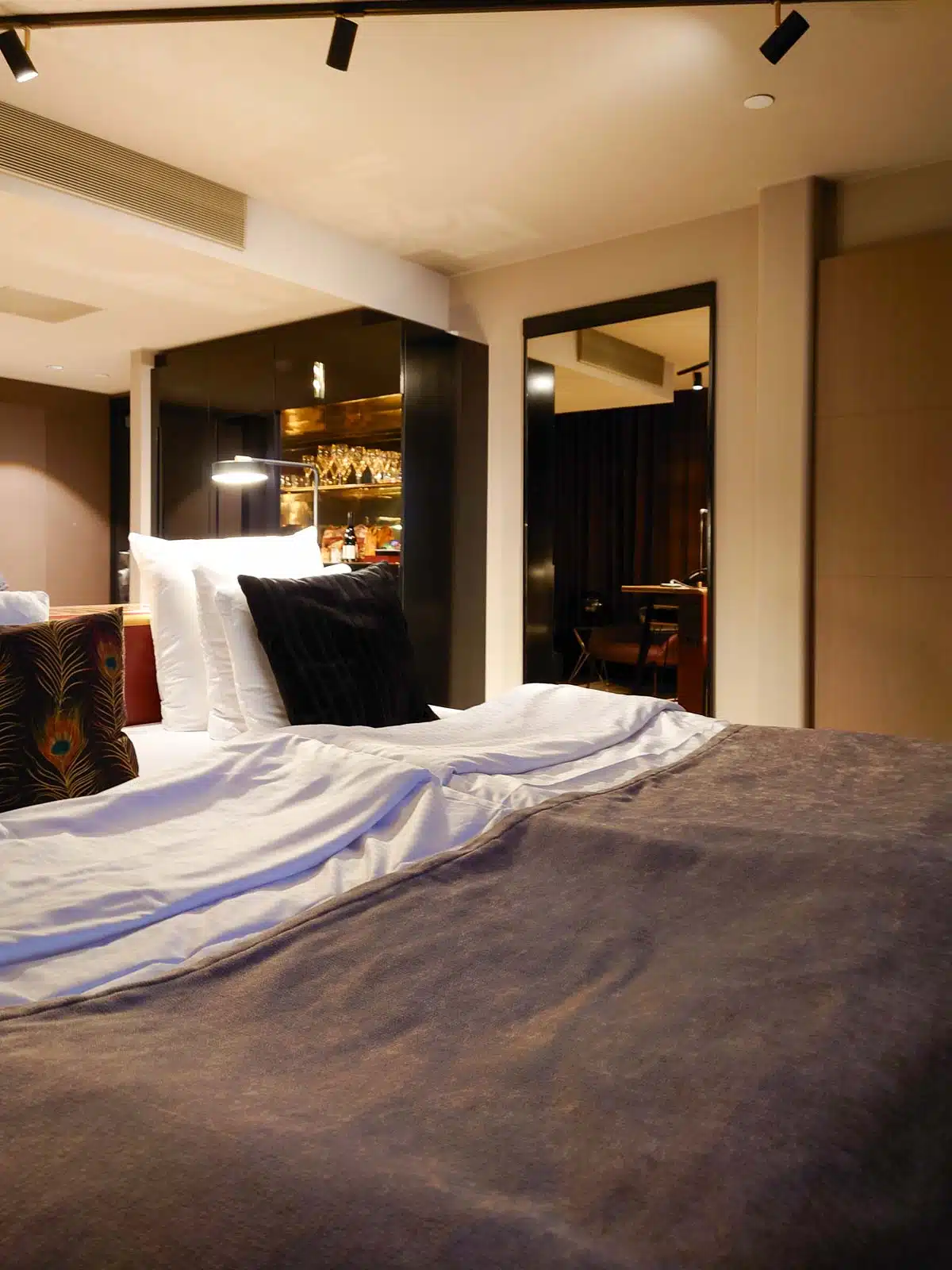 frei stehendes Doppelbett und offene Minibar im Hotelzimmer im Marski