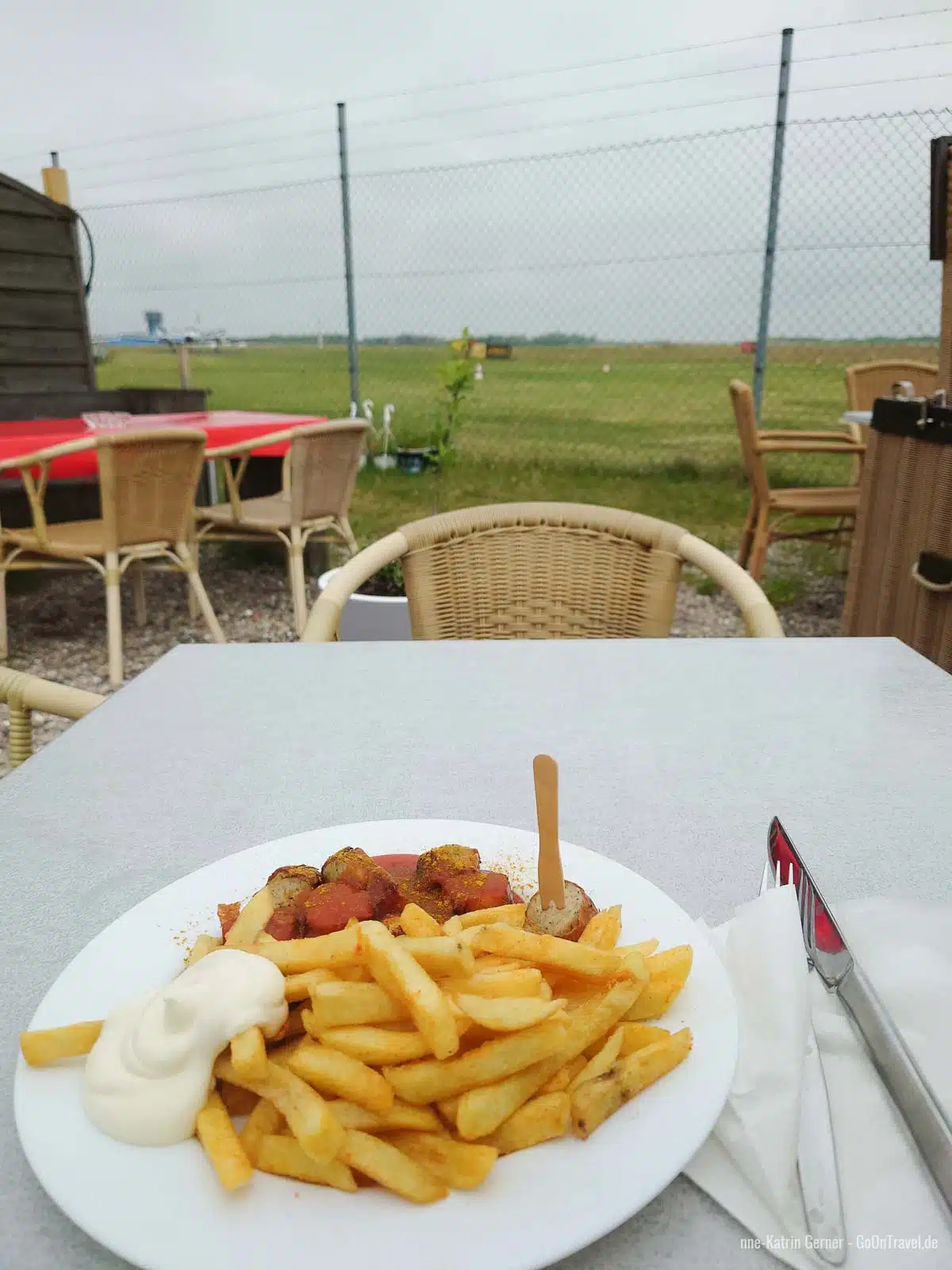 Currywurst Pommes und Blick auf die Rollbahn vom Flughafen Sylt Currywurst Pommes und Blick auf die Rollbahn vom Flughafen Sylt